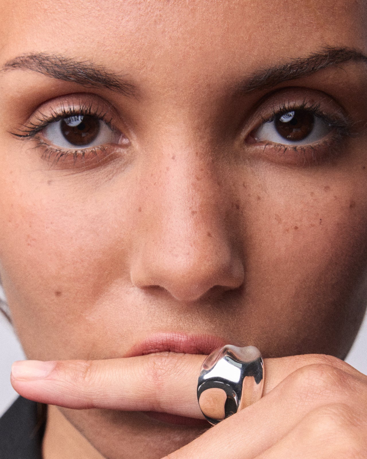 Sculptural silver dome ring with smooth reflective curves, worn on a person’s index finger