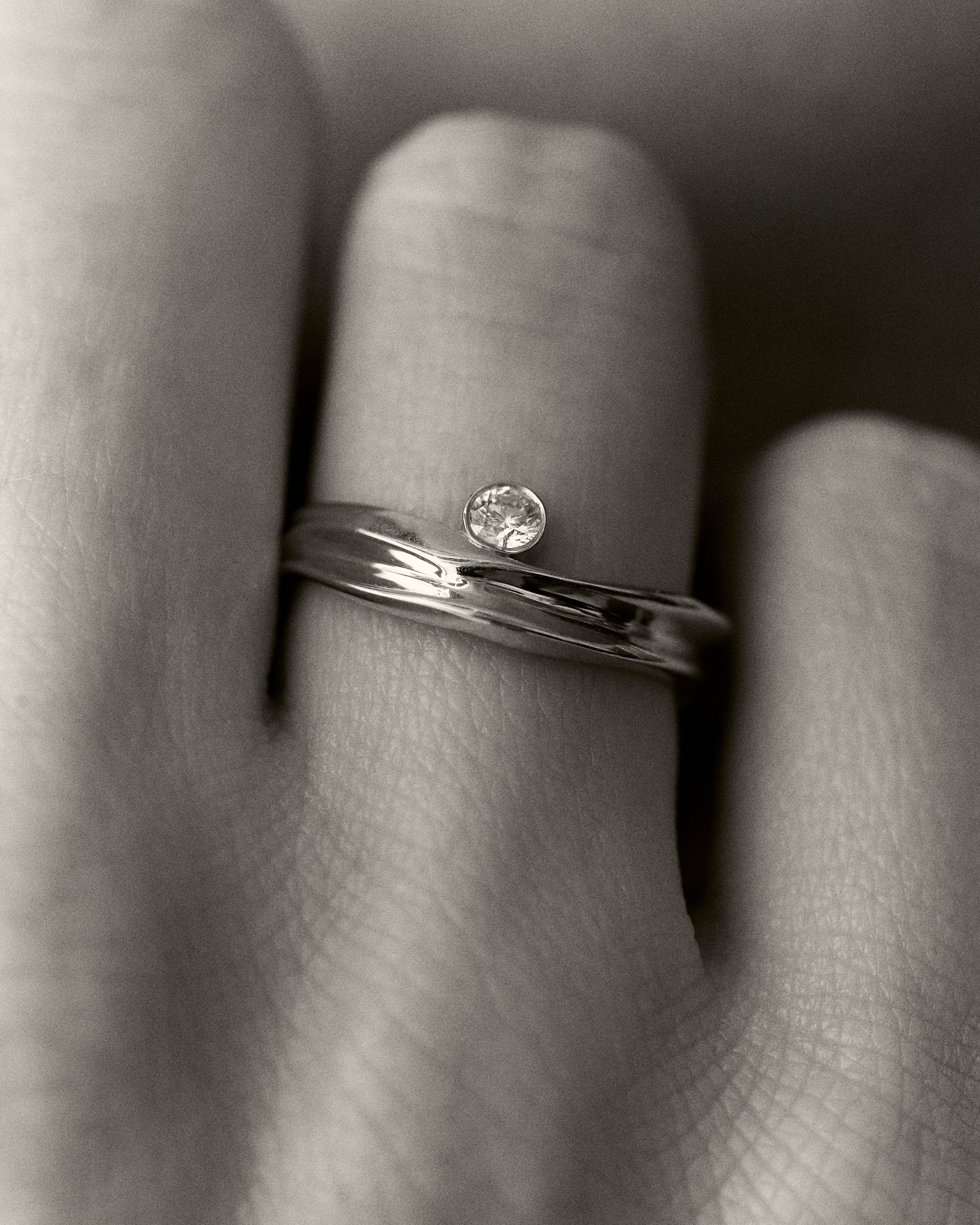 Unique gold solitaire ring featuring a curved band and round diamond, styled as an engagement ring