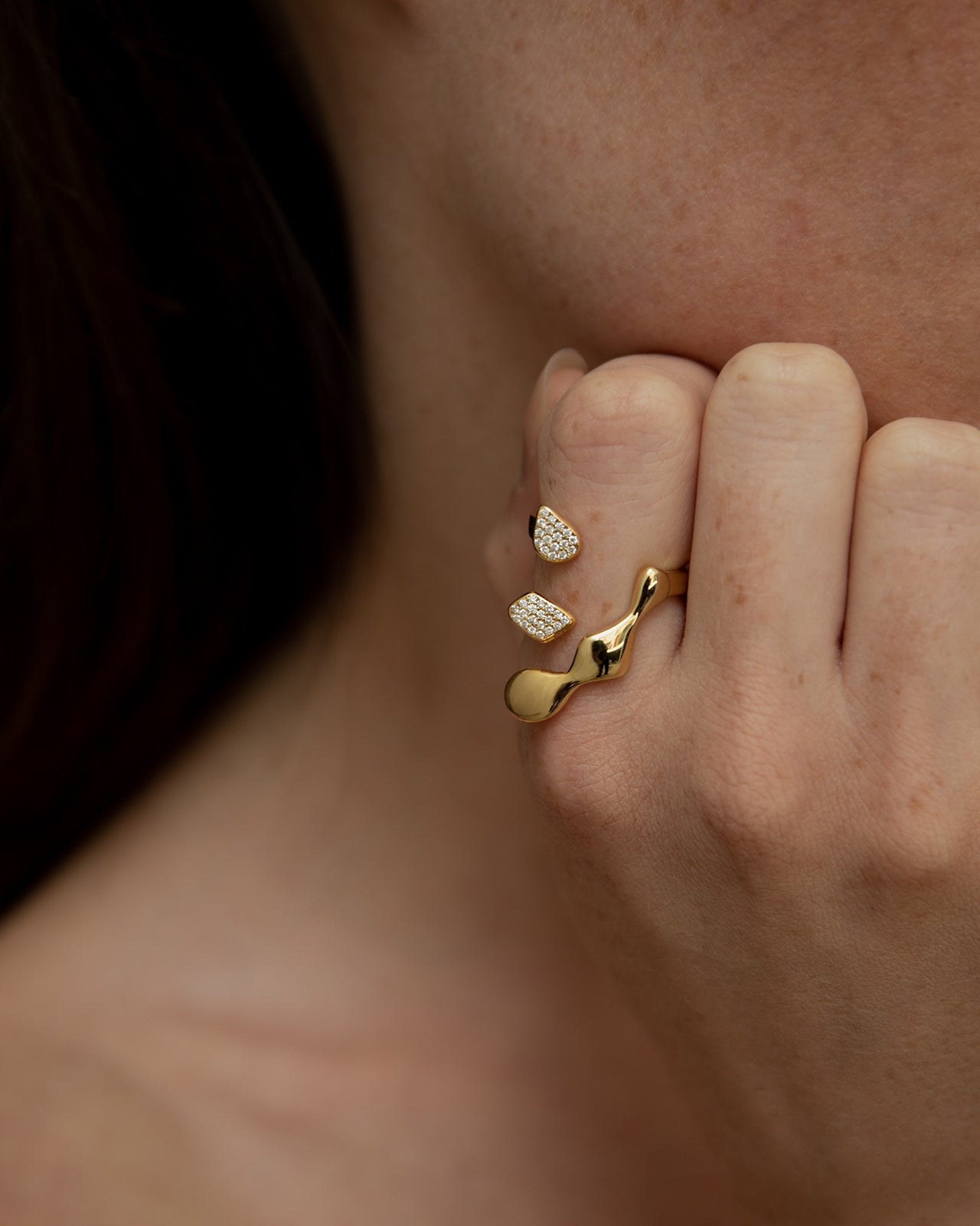 A person's hand showing a Flux Gold Ring with pave diamonds on index finger.