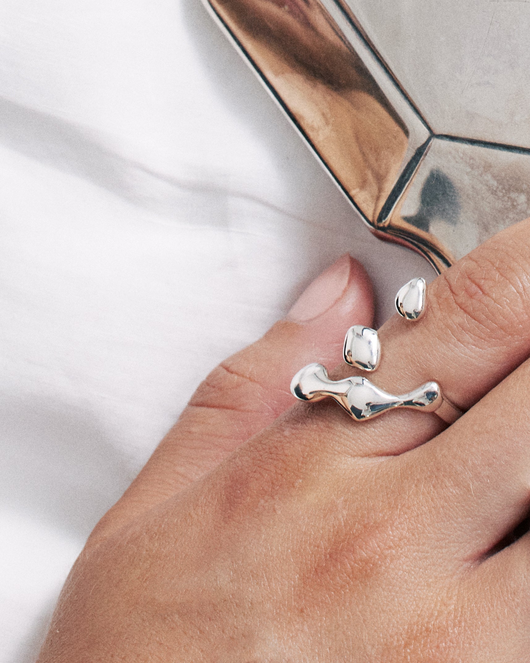 Flux Ring with sculptural design, worn on the hand while holding a silver mirror