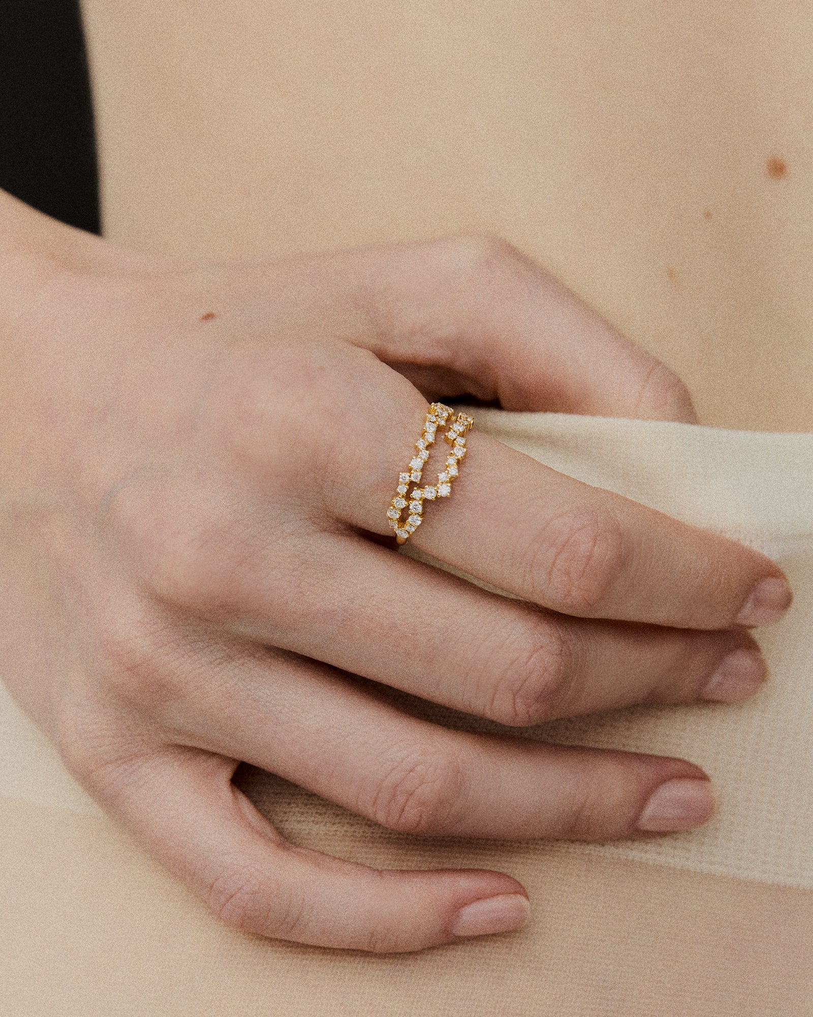 Close-up of a gold ring with unique grooved pattern and diamond accents, showcased on the index finger