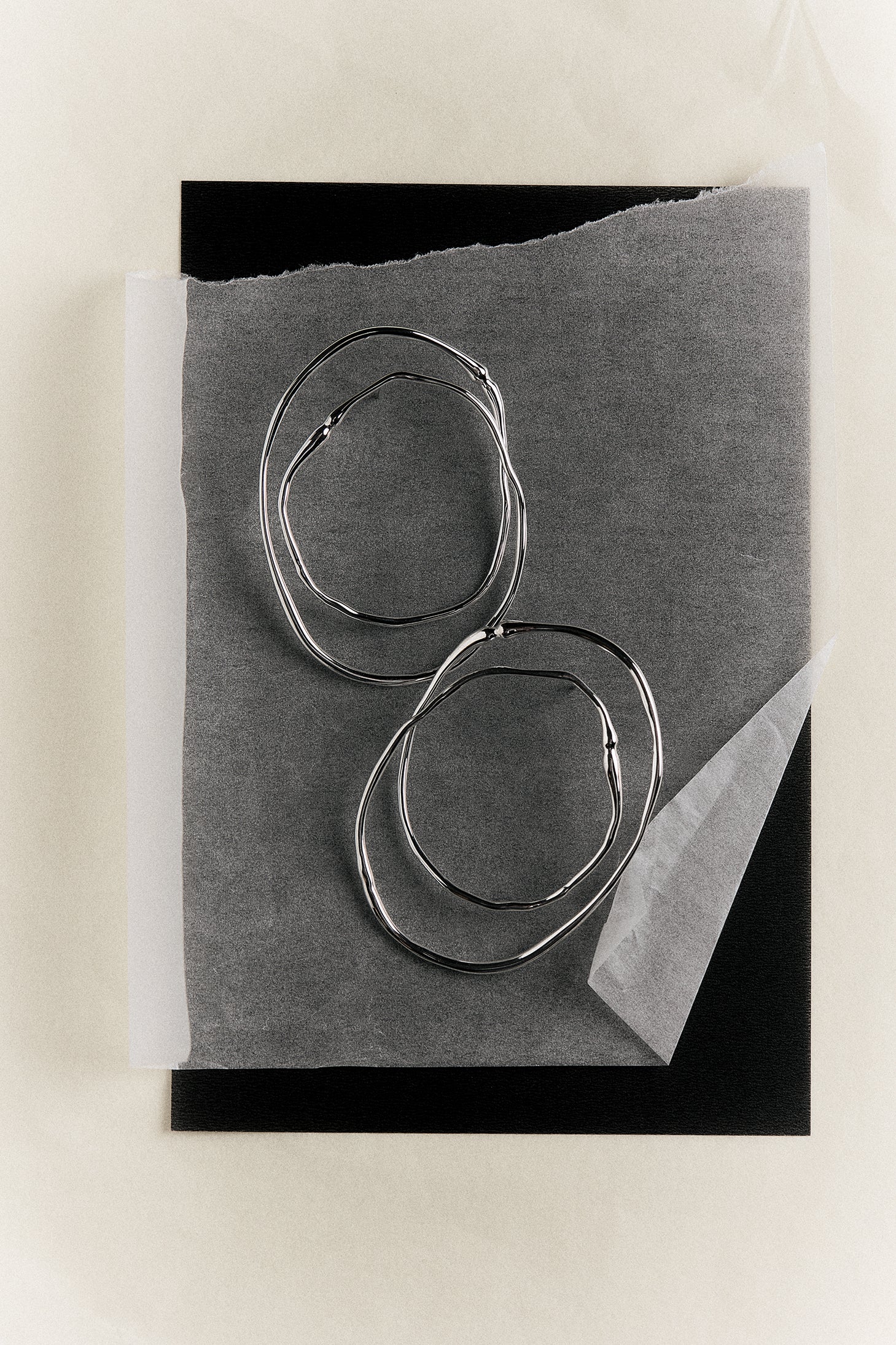 Silver double hoop earrings with a unique design on a piece of paper