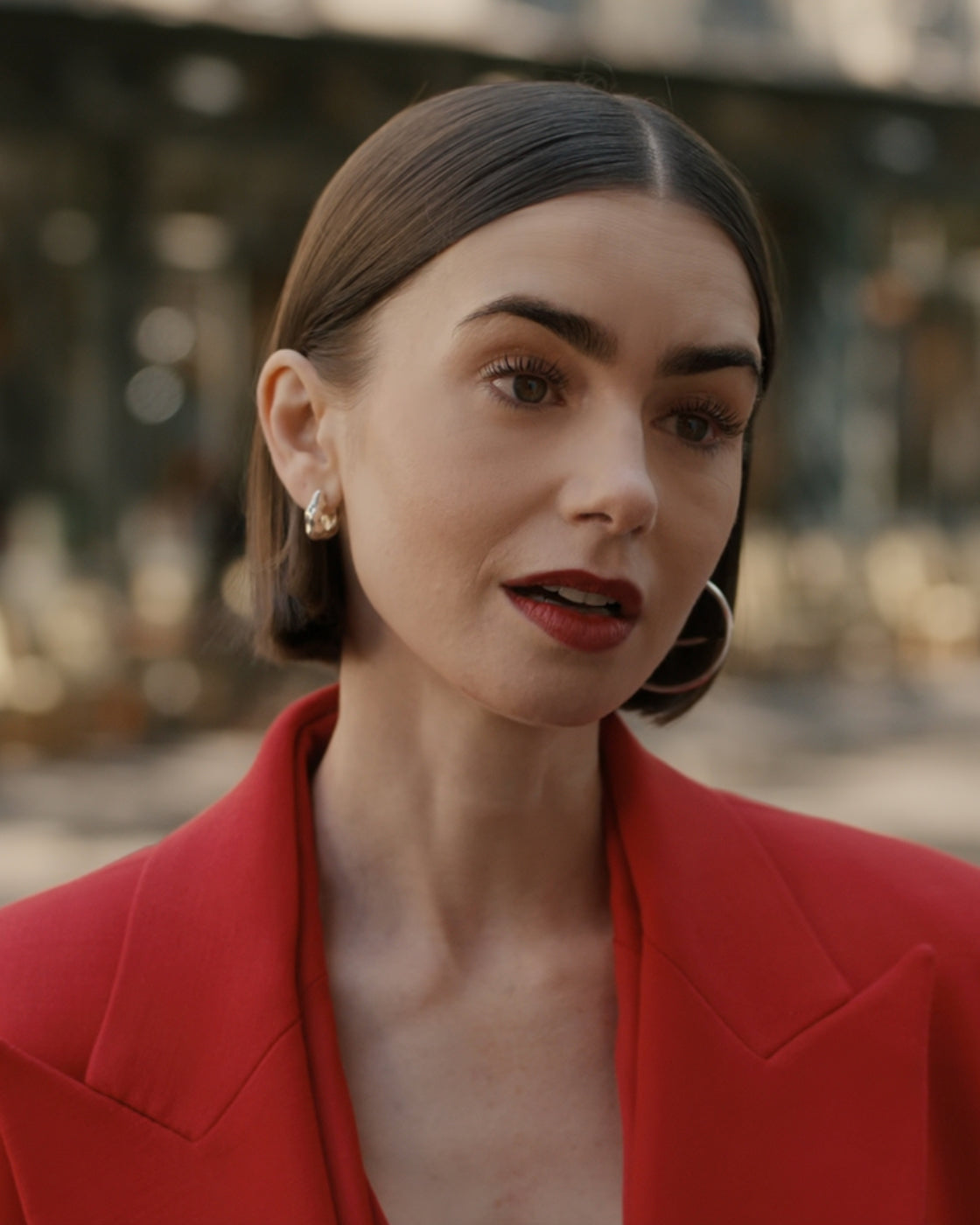 Emily (Lily Collins) wearing Mara Paris Lunar Medium Hinged Earrings talking to another person