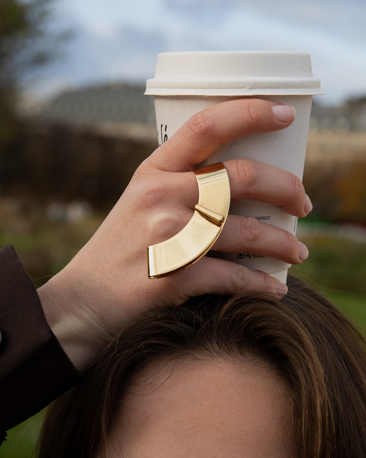 A gold vermeil ring with a deconstructivist architectural design, worn on a middle finger