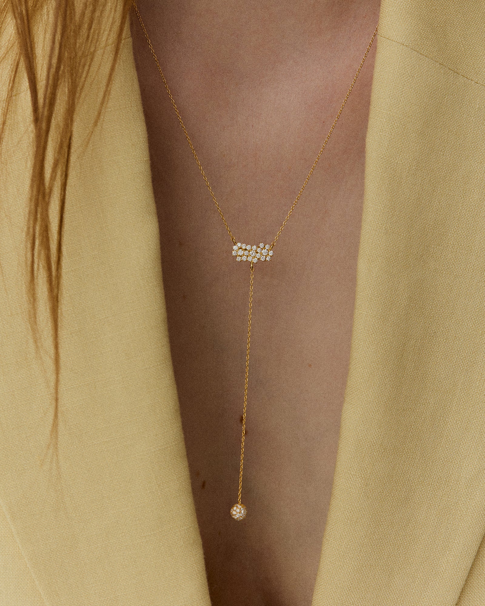 Person wearing a Quiet Intensity Drop Necklace with diamond cluster and pavé-set sphere pendant on a chain