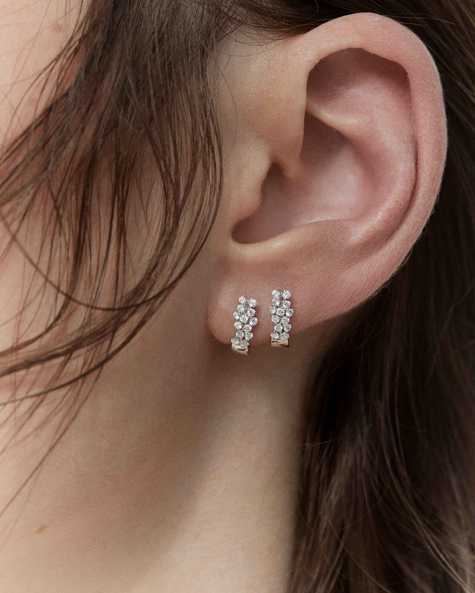Elegant white gold diamond earrings worn side by side on a single ear