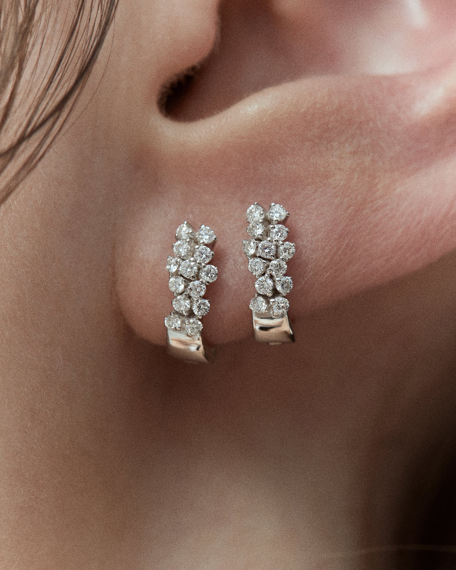 Pair of white gold diamond earrings worn together on one ear